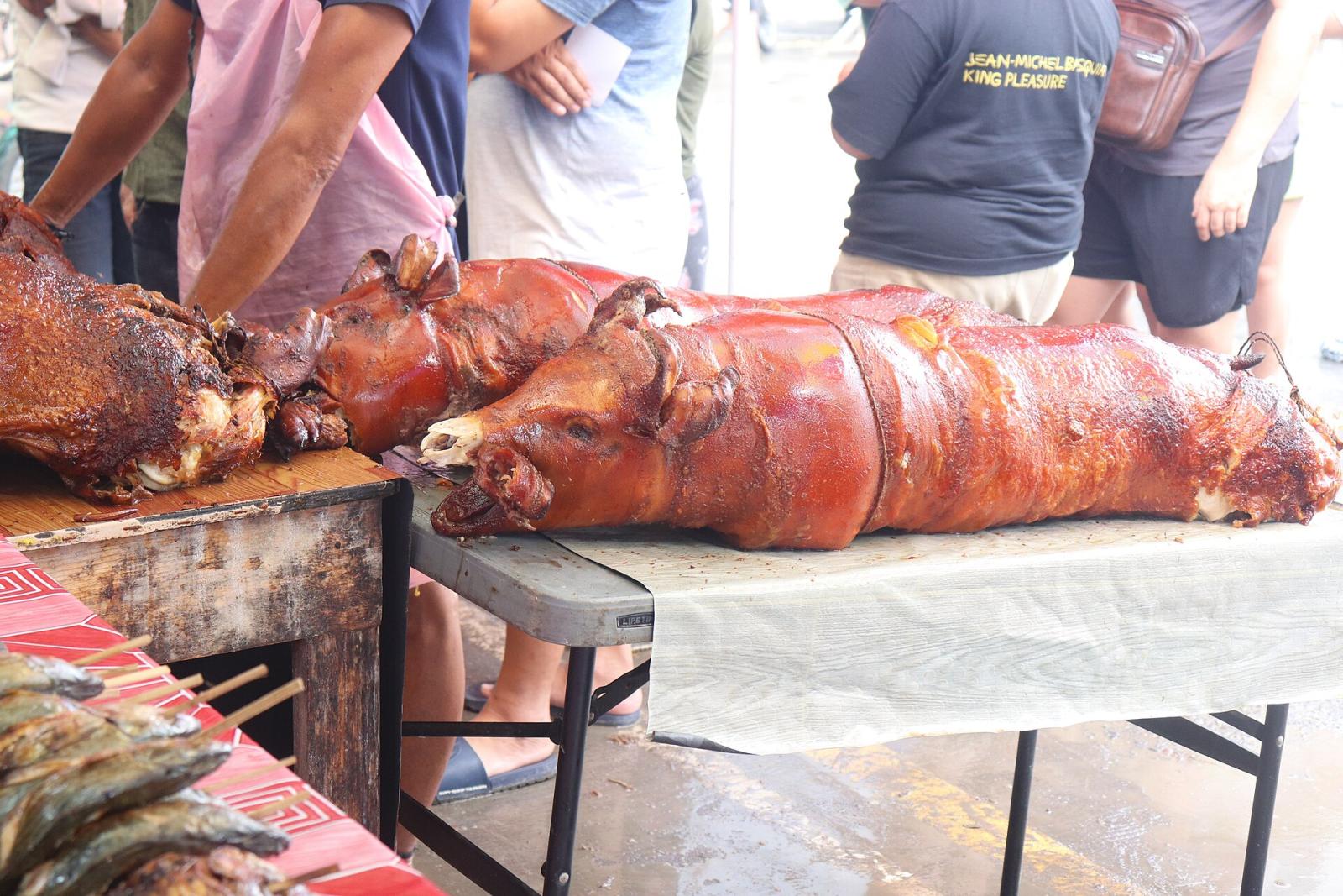 Whole roast pigs lined up on tables at a lechon stall in Talisay, Cebu