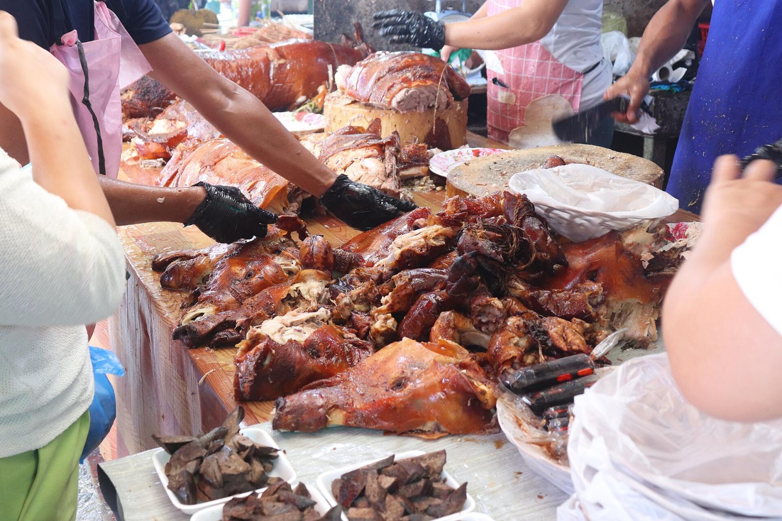 Lechon being chopped and served by the kilo at a market stall in Talisay, Cebu