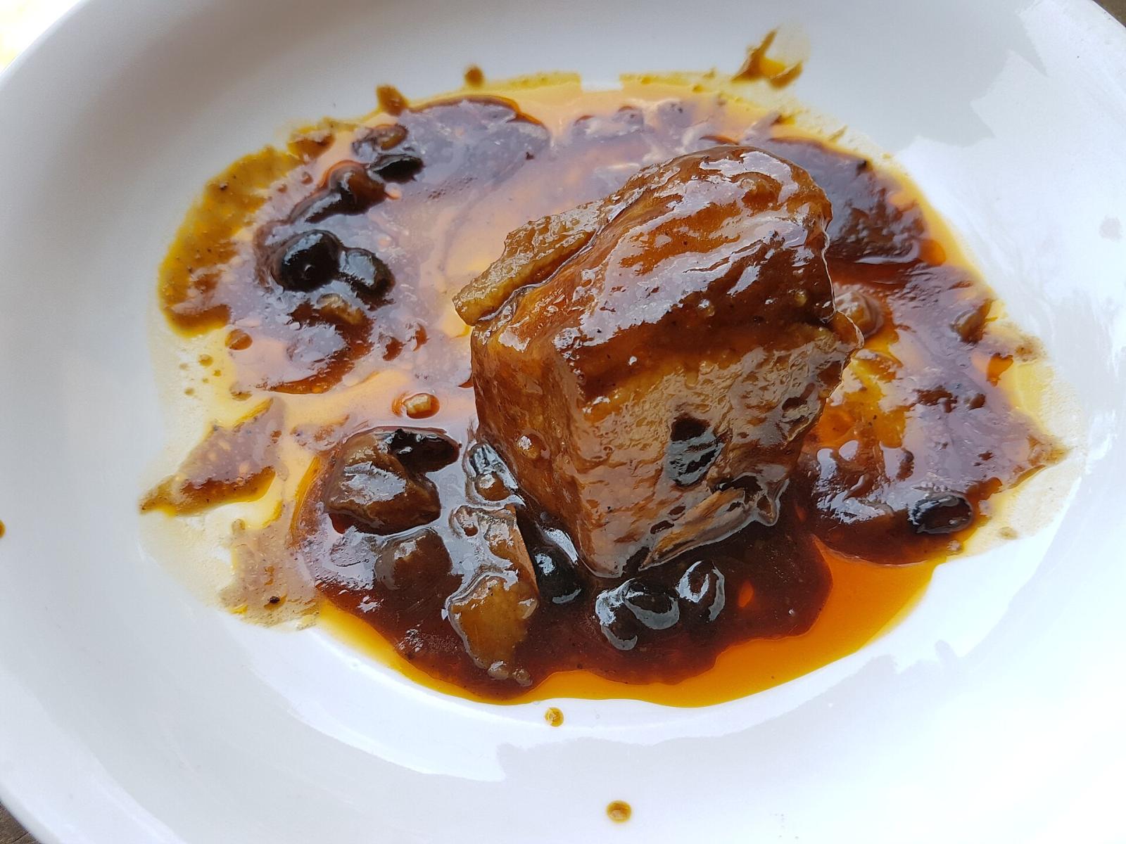 A single piece of humba plated in its reduced sauce with fermented black beans